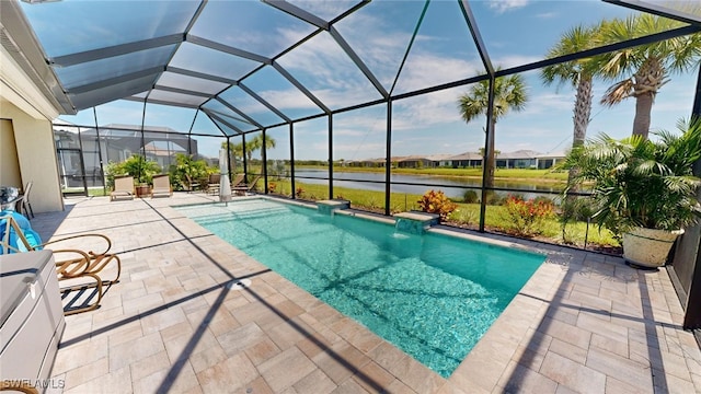 view of pool with pool water feature, glass enclosure, a patio area, and a water view