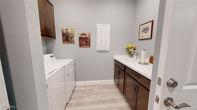 laundry room featuring cabinets, light hardwood / wood-style floors, washing machine and dryer, and sink