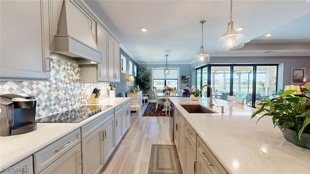 kitchen featuring pendant lighting, custom exhaust hood, plenty of natural light, and sink