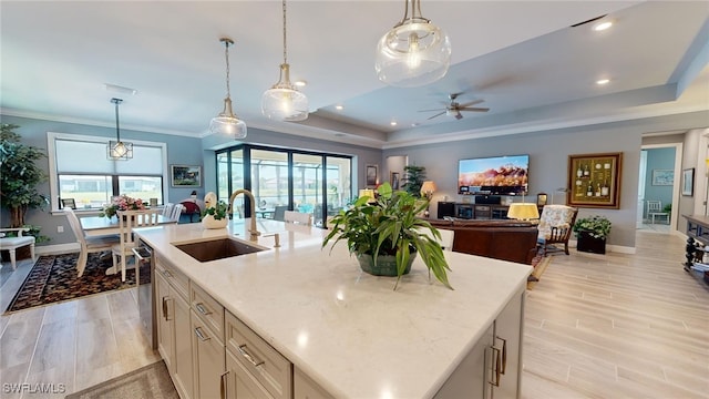 kitchen featuring sink, light stone countertops, a kitchen island with sink, and a wealth of natural light