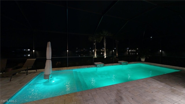 pool at night featuring a patio and a lanai