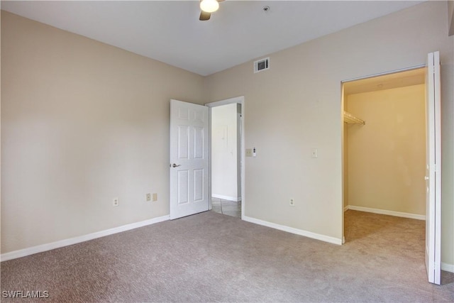 unfurnished bedroom featuring light carpet, a spacious closet, and a closet