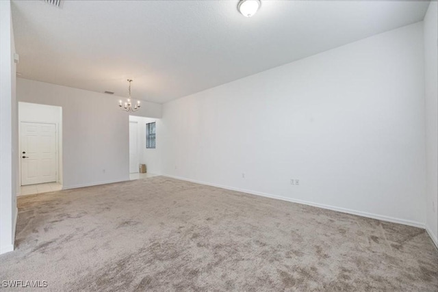 unfurnished room with a notable chandelier and light carpet