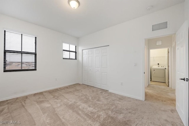 unfurnished bedroom featuring light colored carpet, washer / clothes dryer, and a closet