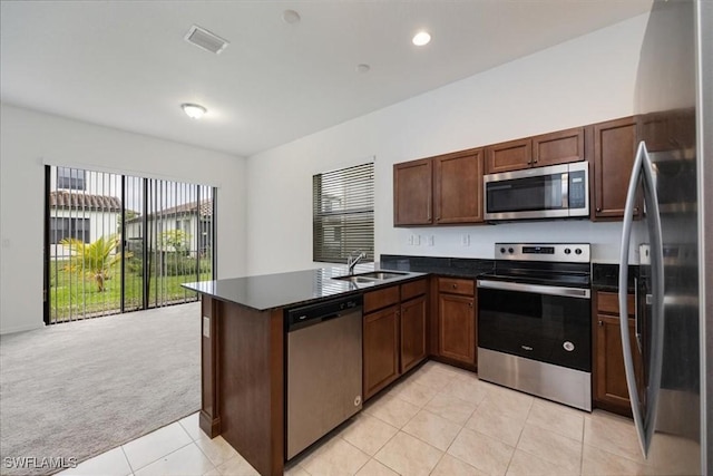 kitchen featuring light carpet, stainless steel appliances, kitchen peninsula, and sink