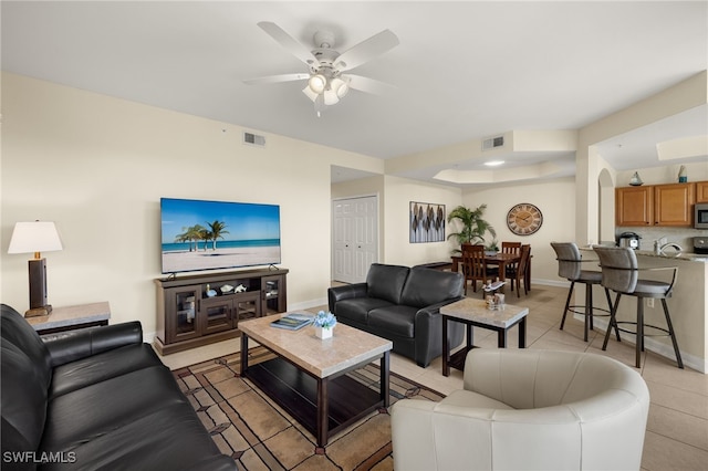 living area with light tile patterned floors, ceiling fan, visible vents, and baseboards