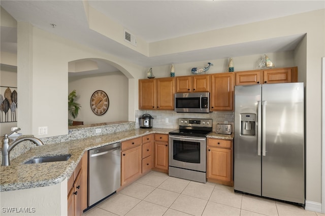 kitchen with visible vents, decorative backsplash, light stone counters, stainless steel appliances, and a sink