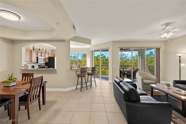 living area with baseboards, visible vents, ceiling fan, and light tile patterned flooring