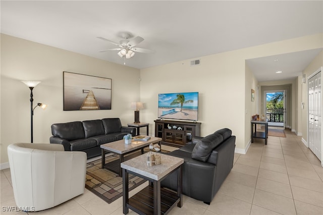 living area with light tile patterned floors, visible vents, a ceiling fan, and baseboards