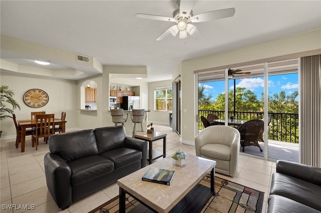 living area with a ceiling fan, light tile patterned flooring, visible vents, and baseboards