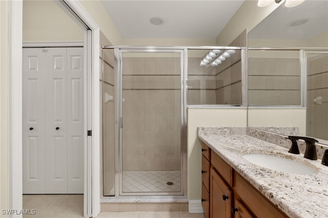 bathroom with a stall shower, tile patterned flooring, a closet, and vanity