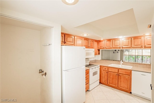 kitchen with light tile patterned floors, white appliances, a tray ceiling, and sink