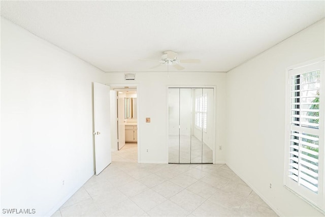 unfurnished bedroom with ceiling fan, a textured ceiling, and a closet