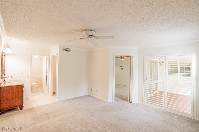 carpeted spare room with ceiling fan, sink, a textured ceiling, and ornamental molding