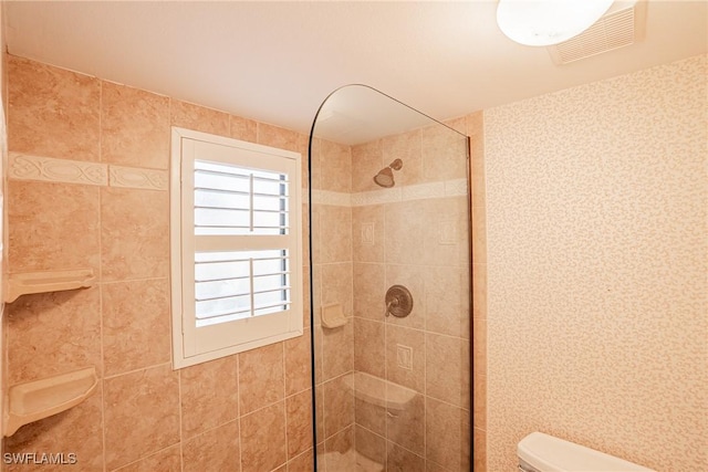 bathroom featuring a tile shower and toilet