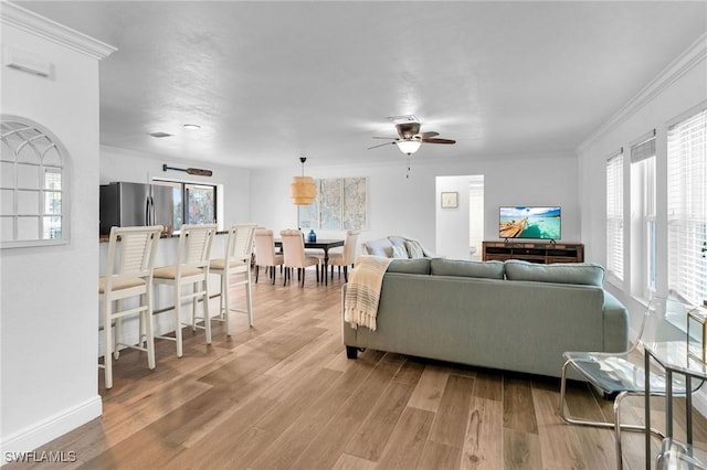 living room featuring a wealth of natural light, light hardwood / wood-style flooring, ceiling fan, and ornamental molding