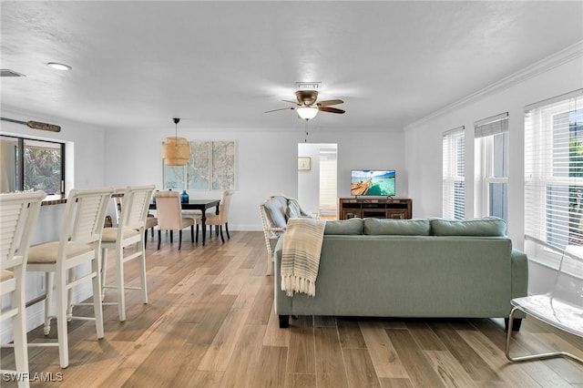 living room with ceiling fan, ornamental molding, and light hardwood / wood-style flooring