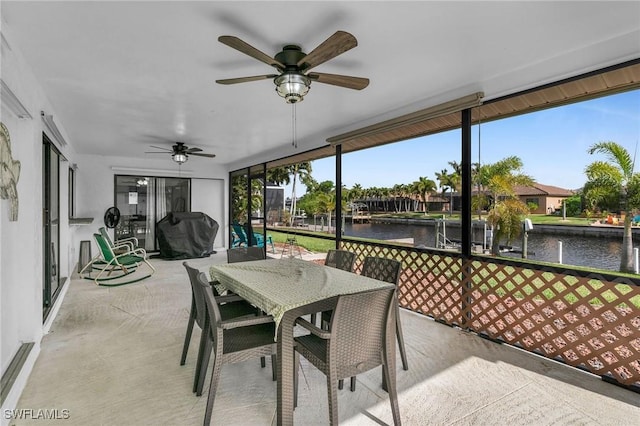 sunroom with ceiling fan and a water view