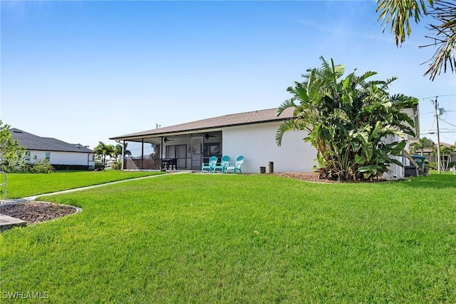 rear view of property with a yard, ceiling fan, and a sunroom