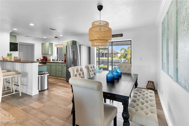 dining area with light hardwood / wood-style floors, sink, and crown molding