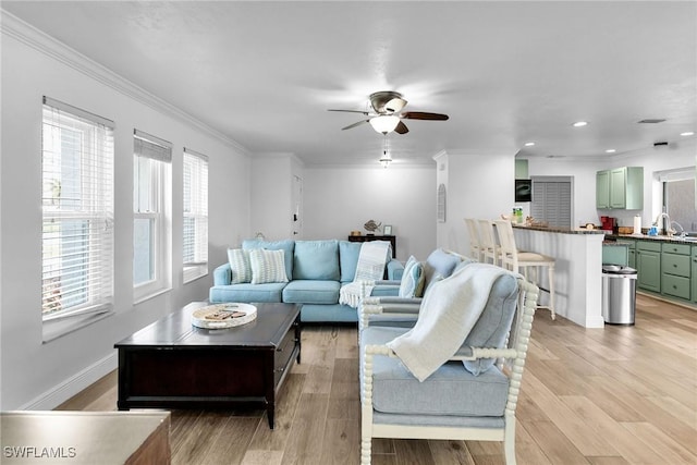 living room featuring light hardwood / wood-style flooring, a healthy amount of sunlight, and ornamental molding