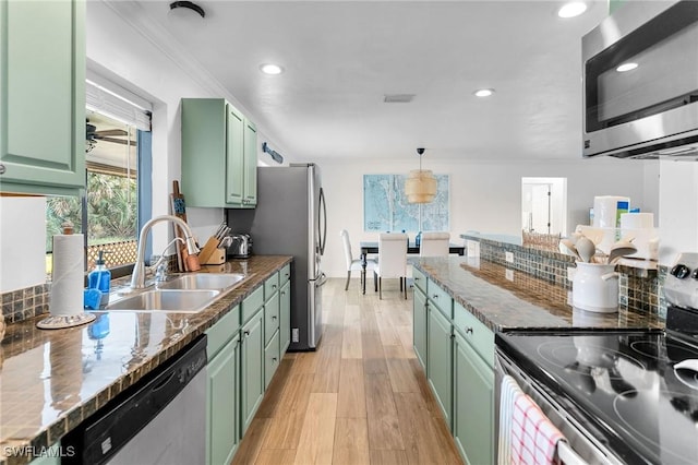 kitchen featuring hanging light fixtures, stainless steel appliances, green cabinetry, and sink