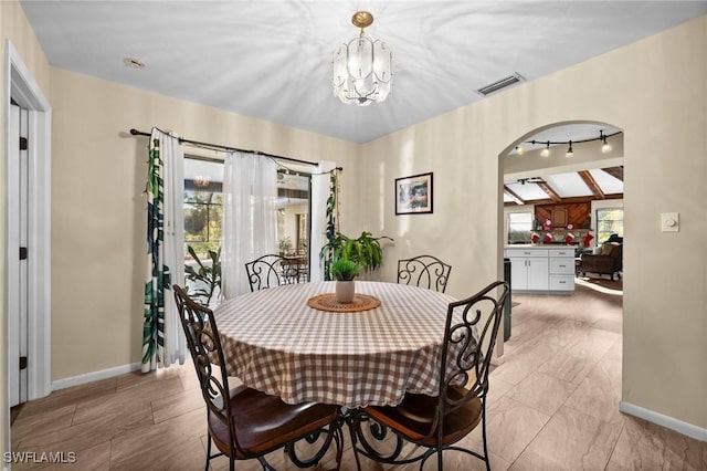 dining room featuring beam ceiling, a healthy amount of sunlight, and a notable chandelier