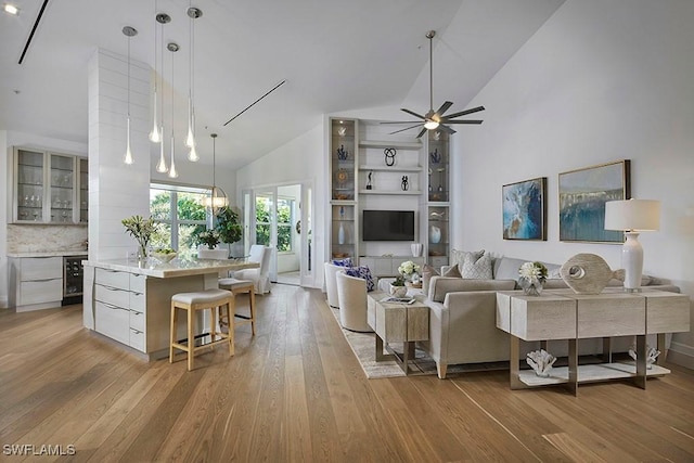 living room with high vaulted ceiling, beverage cooler, light hardwood / wood-style flooring, and ceiling fan