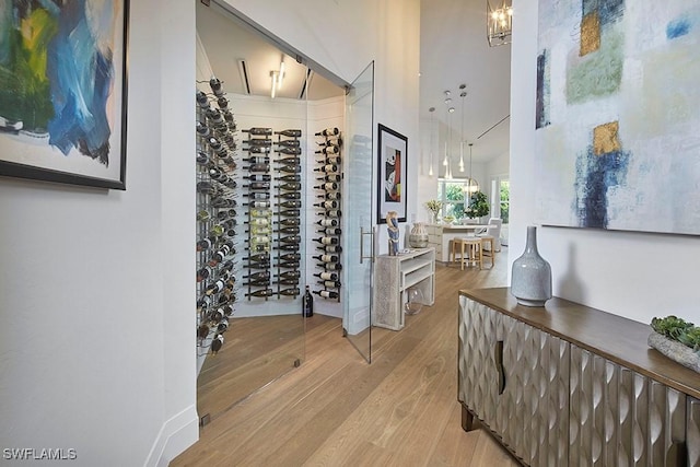 wine cellar featuring an inviting chandelier, hardwood / wood-style flooring, and a high ceiling