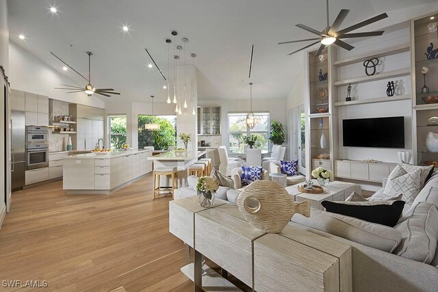 living room featuring ceiling fan, light wood-type flooring, high vaulted ceiling, and a wealth of natural light