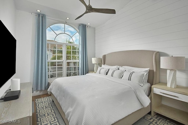 bedroom featuring wooden walls, hardwood / wood-style floors, and ceiling fan