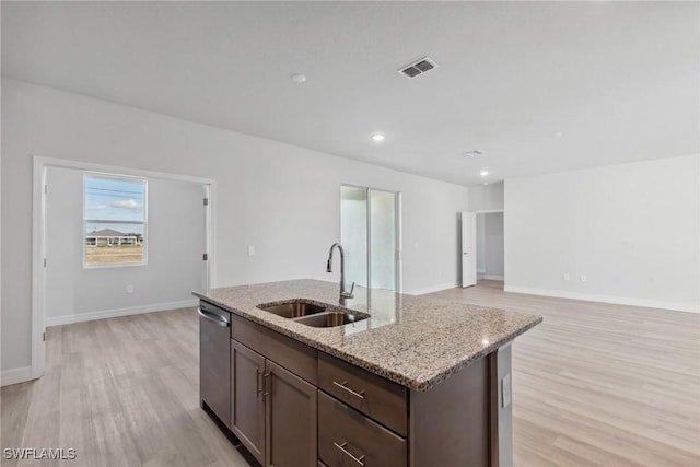 kitchen featuring a center island with sink, sink, light hardwood / wood-style flooring, stainless steel dishwasher, and light stone counters