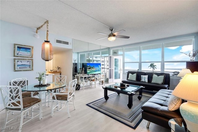 living room with wood-type flooring, a textured ceiling, expansive windows, and ceiling fan