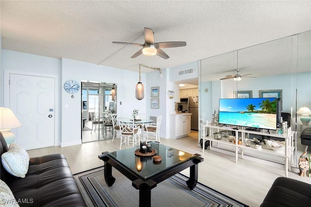 living room featuring ceiling fan and a textured ceiling