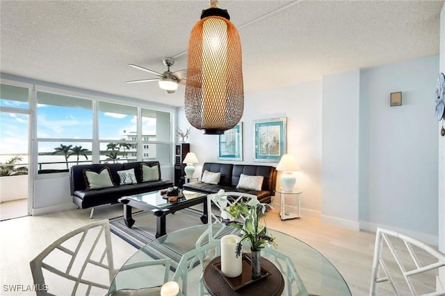 living room with ceiling fan, light wood-type flooring, and a textured ceiling