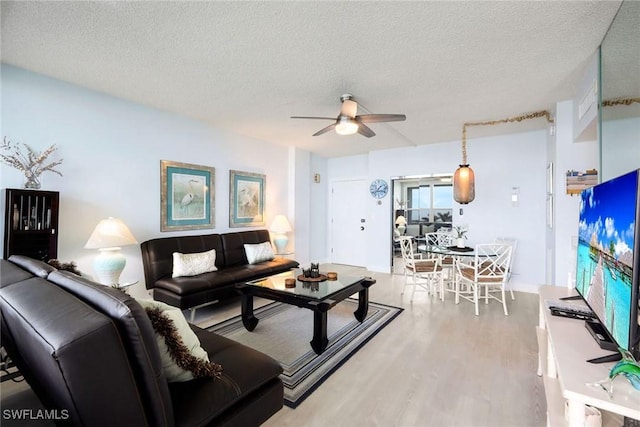 living room featuring a textured ceiling, light hardwood / wood-style floors, and ceiling fan