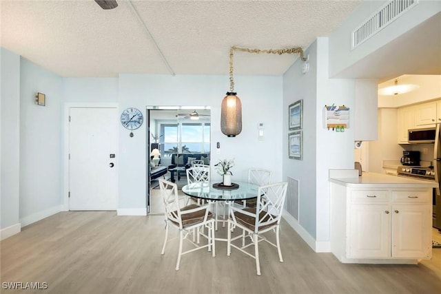 dining area with ceiling fan, a textured ceiling, and light hardwood / wood-style flooring