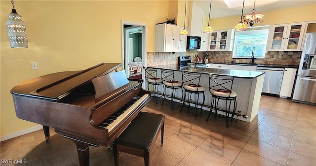 kitchen with decorative light fixtures, stainless steel appliances, white cabinets, and a kitchen bar