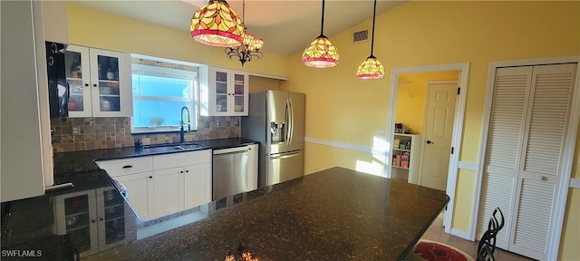 kitchen featuring sink, white cabinetry, hanging light fixtures, dark stone countertops, and appliances with stainless steel finishes