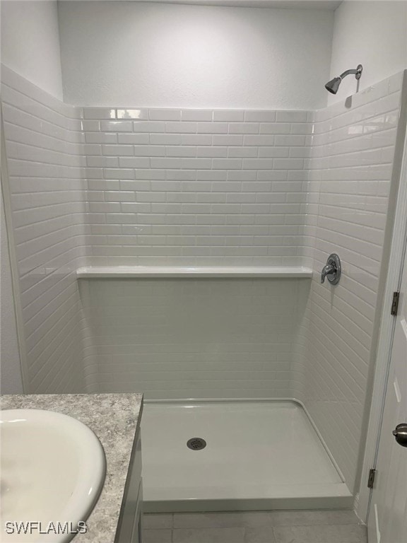 bathroom with tile patterned floors, vanity, and tiled shower