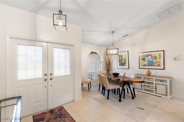 foyer entrance with a chandelier, vaulted ceiling, and light tile patterned flooring