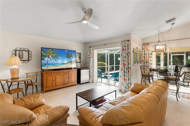 tiled living room with ceiling fan with notable chandelier and lofted ceiling