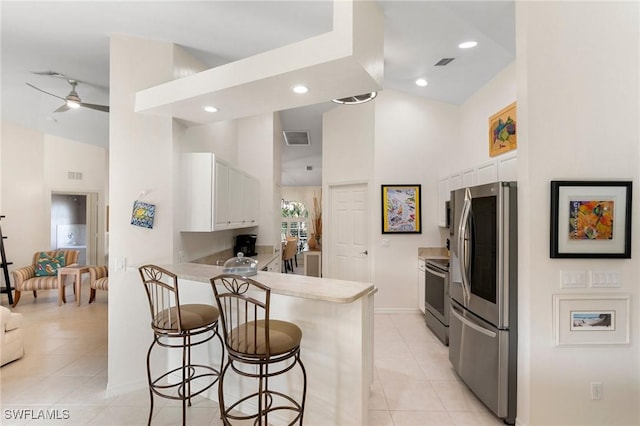 kitchen featuring white cabinets, ceiling fan, appliances with stainless steel finishes, a kitchen bar, and kitchen peninsula