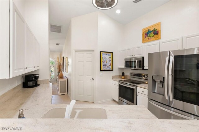 kitchen featuring sink, white cabinets, light tile patterned flooring, and appliances with stainless steel finishes