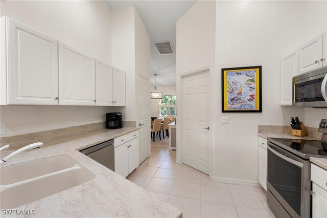 kitchen featuring light stone countertops, stainless steel appliances, light tile patterned floors, high vaulted ceiling, and white cabinetry