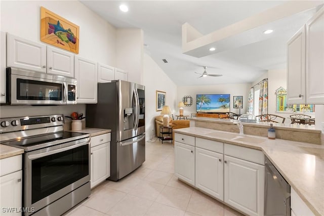 kitchen with lofted ceiling, sink, ceiling fan, white cabinetry, and stainless steel appliances