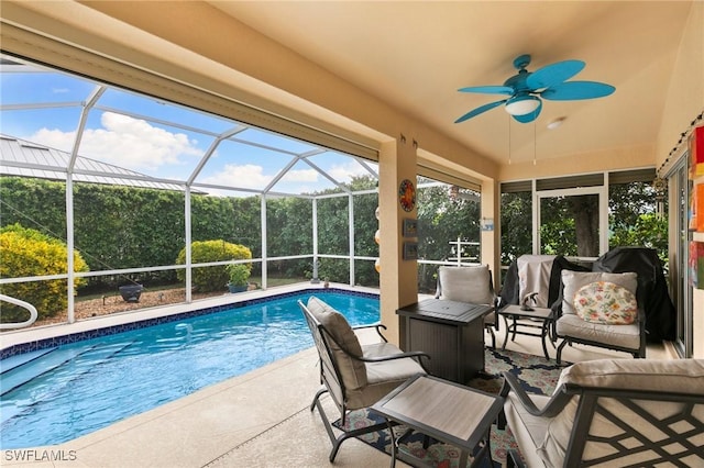 view of swimming pool with glass enclosure, ceiling fan, and a patio area