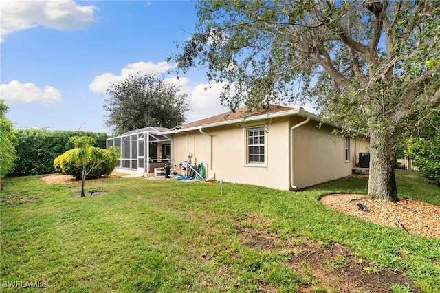 back of property featuring a lawn, glass enclosure, and central air condition unit