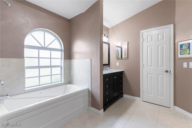 bathroom featuring tile patterned floors, vanity, lofted ceiling, and a tub to relax in