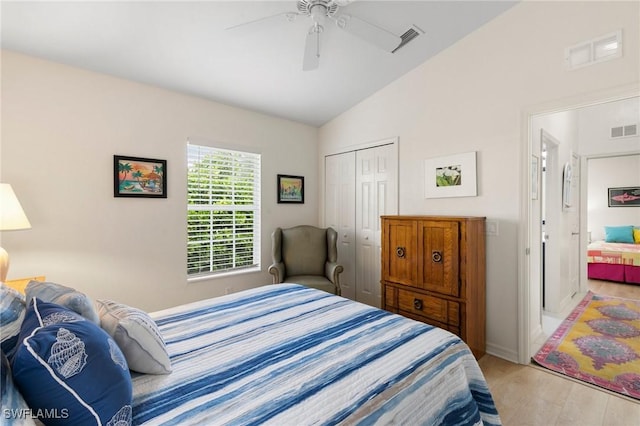 bedroom with ceiling fan, a closet, light hardwood / wood-style floors, and lofted ceiling